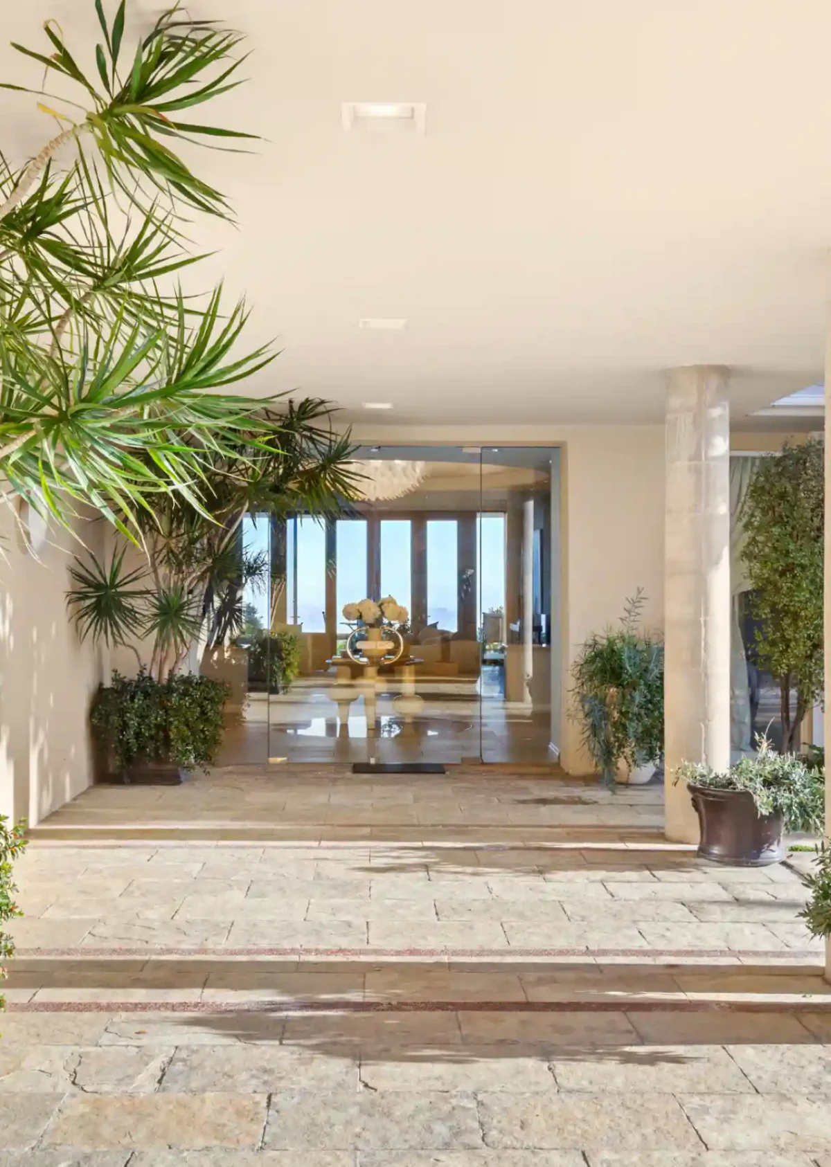 Stone-floored entrance loggia lined with palms opening to an ocean view